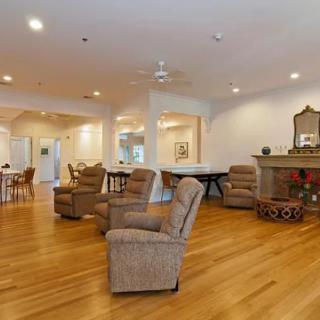 A spacious living room with multiple recliner chairs, a fireplace, and hardwood flooring.