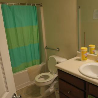 A compact bathroom with a colorful shower curtain and neatly arranged toiletries on the counter.