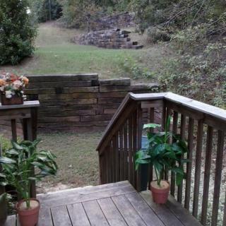 A wooden deck with potted plants leads to a grassy backyard.