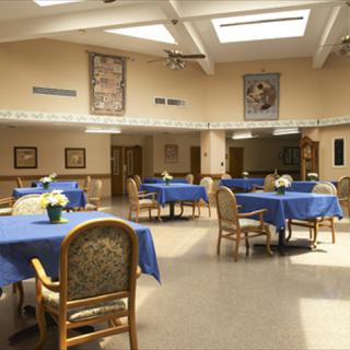 A spacious dining area with tables covered in blue tablecloths and decorated with flowers.