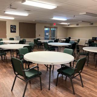 A spacious community room set up with round tables and chairs, ready for an event or gathering.