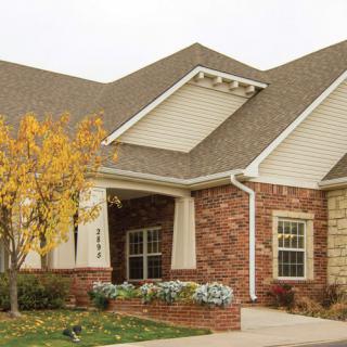 A suburban brick house with a tree in autumn.