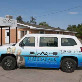 A parked van with business advertising on its side in front of a building.