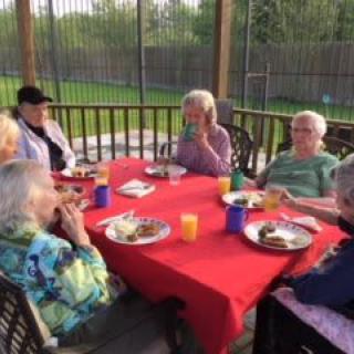 A group of elderly people enjoying a meal together outdoors on a patio.