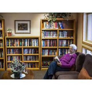A senior individual enjoying a peaceful moment of reading in a cozy library setting.