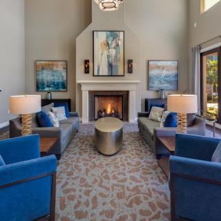 A modern living room with blue furniture, featuring a central fireplace and contemporary artwork.