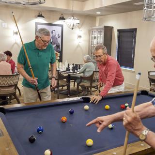 A group of men playing billiards in an indoor recreational room.