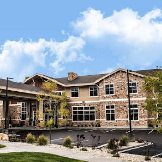 A modern residential building featuring a blend of stone and wood architecture, set against a clear blue sky.