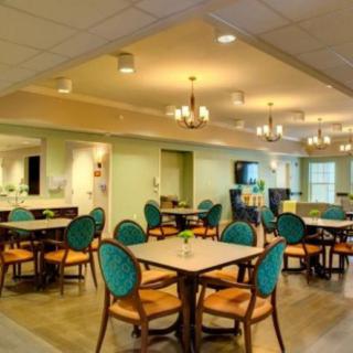 A modern dining area with elegantly arranged tables and chairs, featuring chandeliers for ambient lighting.