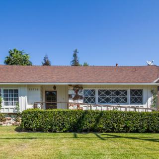 A single-story house with a well-maintained front yard and clear blue sky.