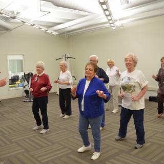A group of seniors participating in a dance class indoors.