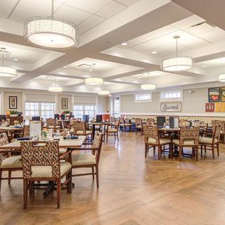 A spacious dining hall with elegant lighting and neatly arranged tables and chairs.