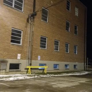 An exterior view of a brick building at night, showcasing its windows and surrounding parking lot.