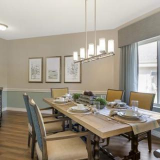A beautifully set dining room with a large wooden table, elegant chairs, and a modern chandelier.
