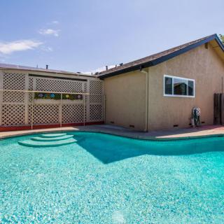 A backyard with a swimming pool and a house under a clear blue sky.