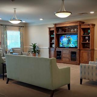 A cozy living room with a large sofa, entertainment center, and elegant lighting.
