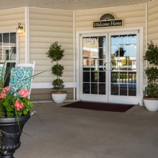 A welcoming entrance with potted plants and a 'Welcome Home' sign.