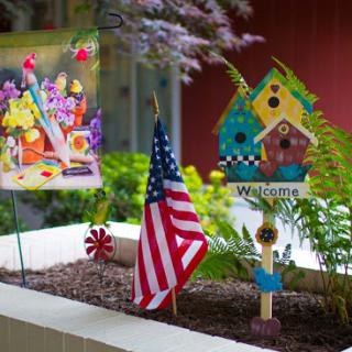 A vibrant garden display featuring a welcoming atmosphere with colorful decorations and an American flag.