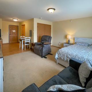A cozy and well-furnished bedroom with a bed, armchairs, and a small dining area.