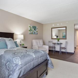 A modern bedroom with a comfortable bed, stylish decor, and a small seating area.