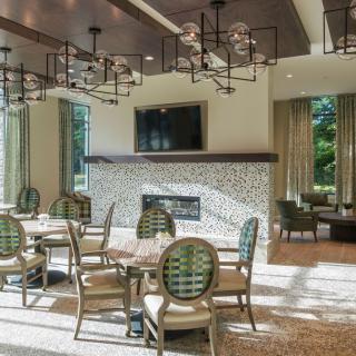 A modern dining area with elegant chandeliers, a fireplace, and ample natural light.