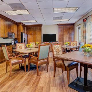 A modern dining area with wooden furniture and bright sunflowers on the tables.