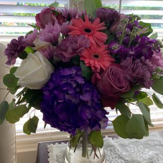 A vibrant bouquet featuring a mix of purple, pink, and white flowers, perfect for brightening any space.