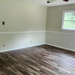An empty room with hardwood floors and a ceiling fan.