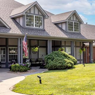 A picturesque suburban house with a well-maintained lawn and an American flag displayed on the porch.