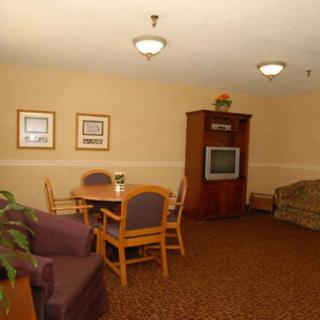 A cozy living room with a television, comfortable seating, and a dining table.