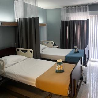 A clean and organized hospital room with two beds separated by curtains.