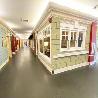 A well-lit indoor hallway decorated with house-like facades and large windows.