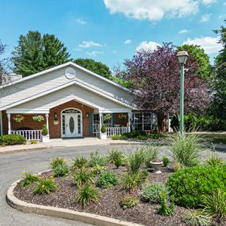 A scenic view of a building entrance surrounded by lush greenery and a well-maintained garden.