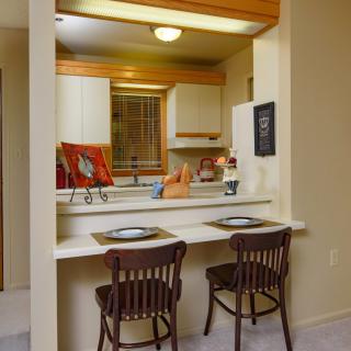 A cozy kitchen with a dining counter and bar stools, featuring warm lighting and decor.