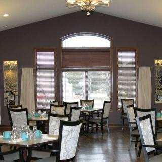 An elegant dining room with neatly arranged tables and chairs, featuring large windows that let in natural light.