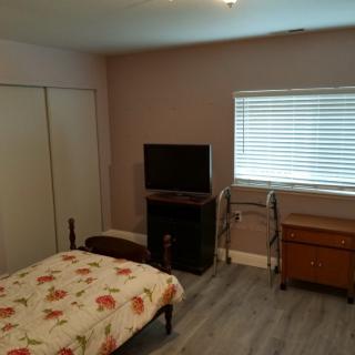 A cozy bedroom featuring a bed with floral bedding, a TV, and a window with blinds.