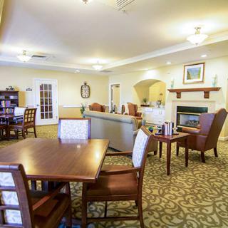 A cozy interior space with dining tables and chairs, featuring a living room area with a carpeted floor.
