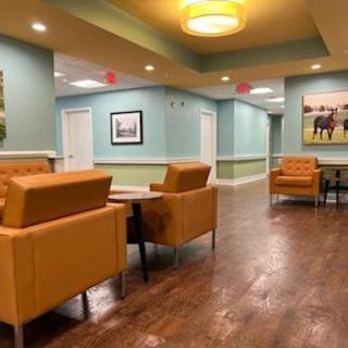 A cozy waiting room with orange chairs and wall art.