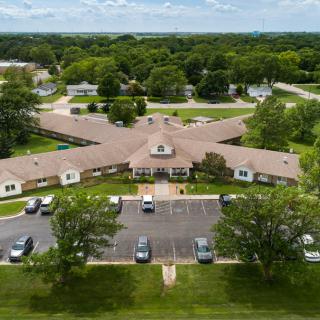 Aerial view of a building surrounded by trees and a parking lot.
