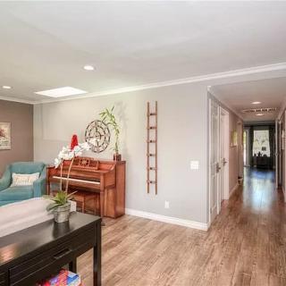 A modern living room with a piano and decorative elements, leading to a hallway.