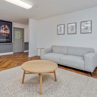 A cozy living room with a minimalist design featuring a gray sofa, wooden coffee table, and wall art.