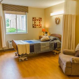 A cozy hospital room with a bed, chair, and decorative elements.