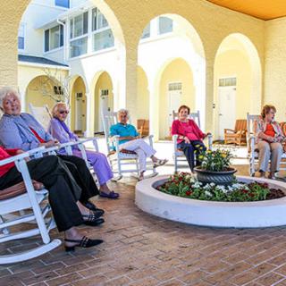 A group of seniors enjoying a leisurely afternoon in rocking chairs at a retirement community courtyard.