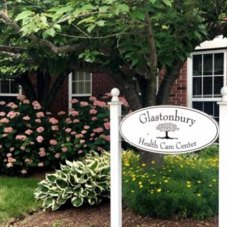 A health care center sign in front of a building surrounded by flowers and greenery.