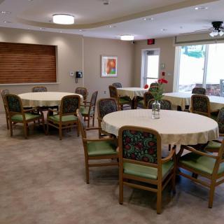 A well-lit dining room with round tables and chairs arranged neatly.