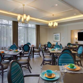 A cozy dining room with neatly arranged tables and chairs, featuring elegant lighting and modern decor.