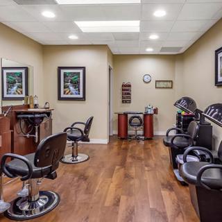 A well-lit barber shop interior with multiple chairs and mirrors, featuring wooden flooring and stylish decor.