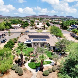 A serene aerial view of a suburban home featuring solar panels and lush landscaping.
