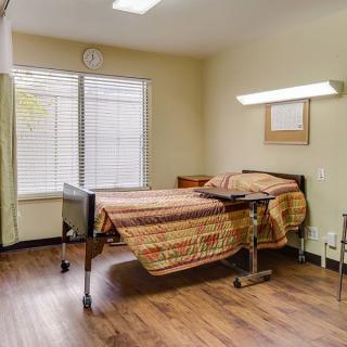 A hospital room with a single bed and window, featuring simple decor.