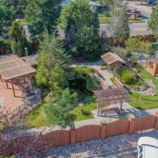 Aerial view of a beautifully landscaped garden featuring pergolas, lush greenery, and well-maintained outdoor spaces surrounded by a decorative fence.